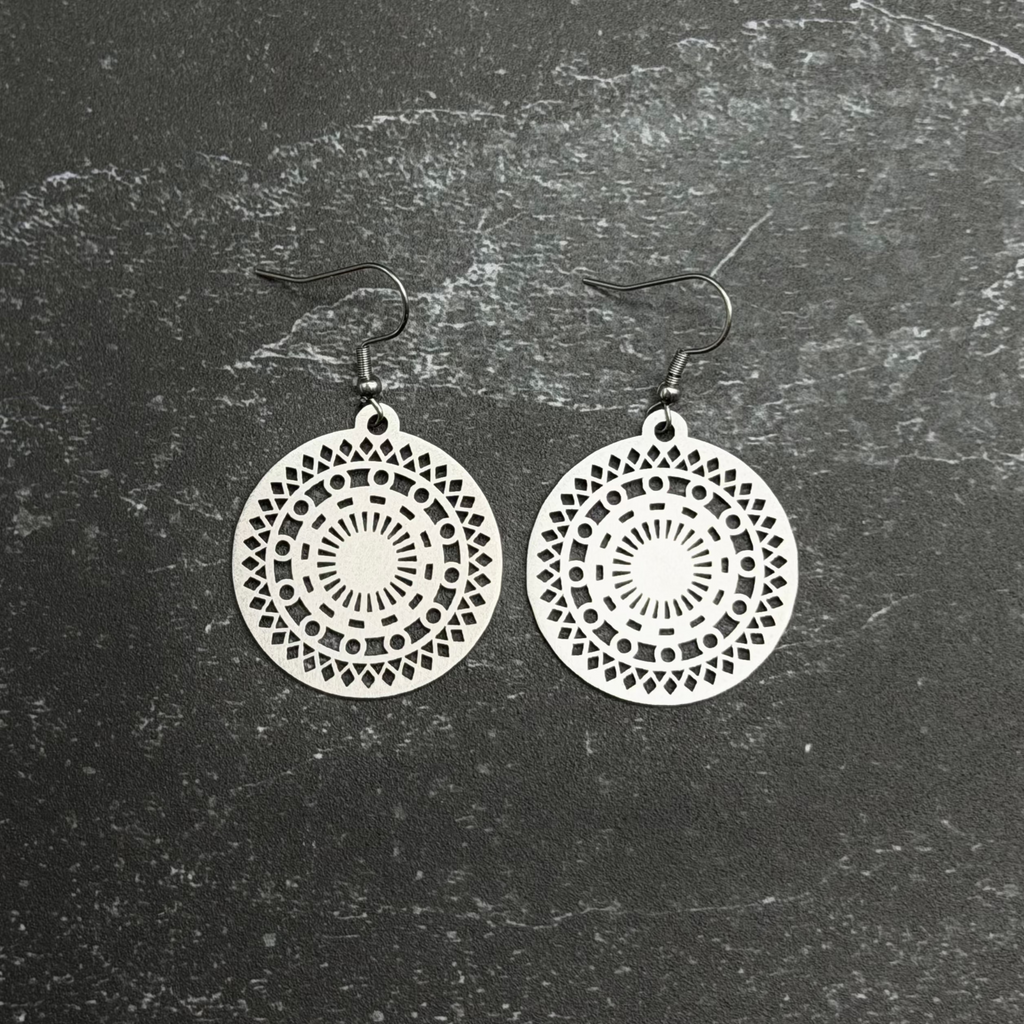 Stainless steel mosaic earrings with intricate designs on a textured black background