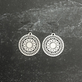 Stainless steel mosaic earrings with intricate designs on a textured black background
