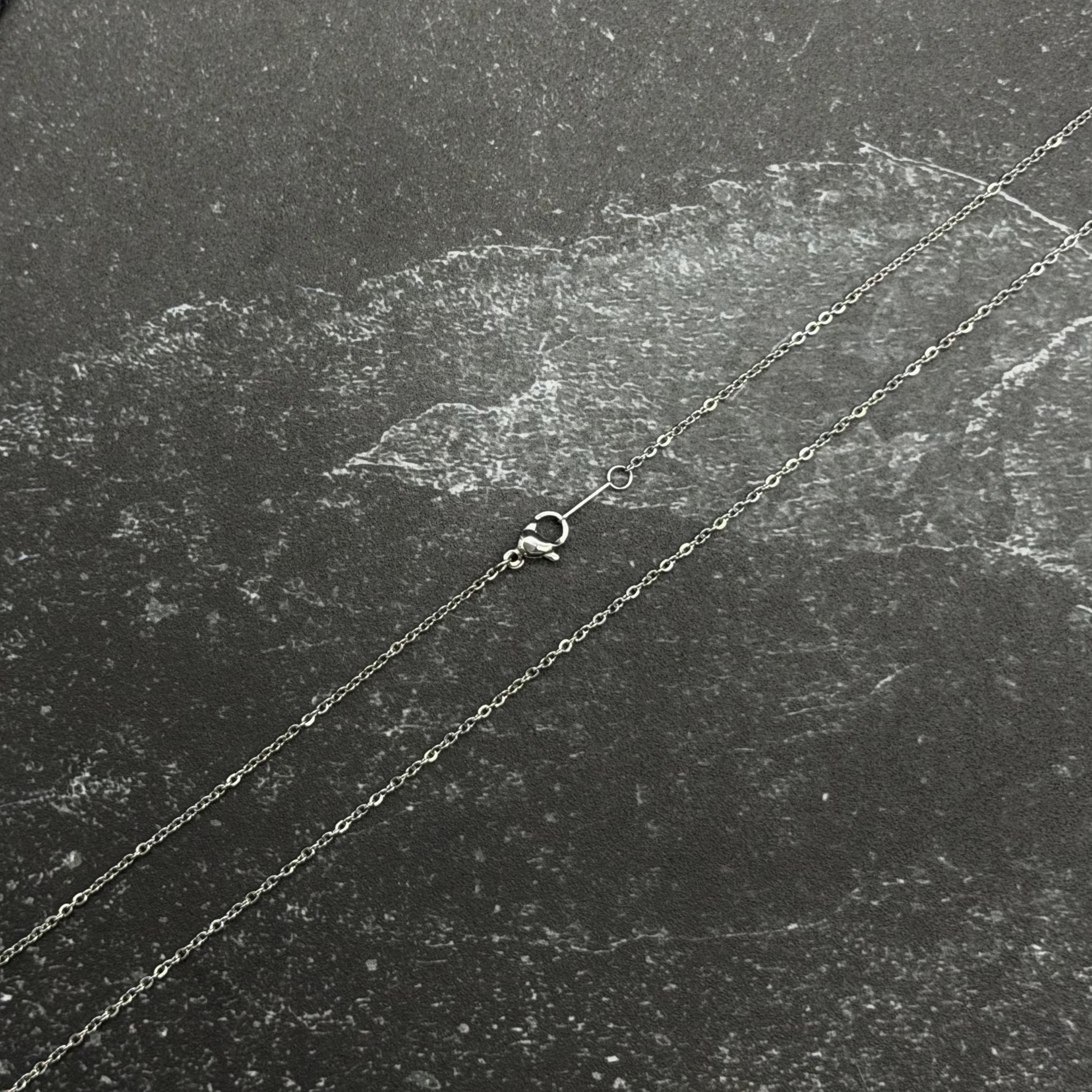 Stainless steel chain necklace on black surface. 