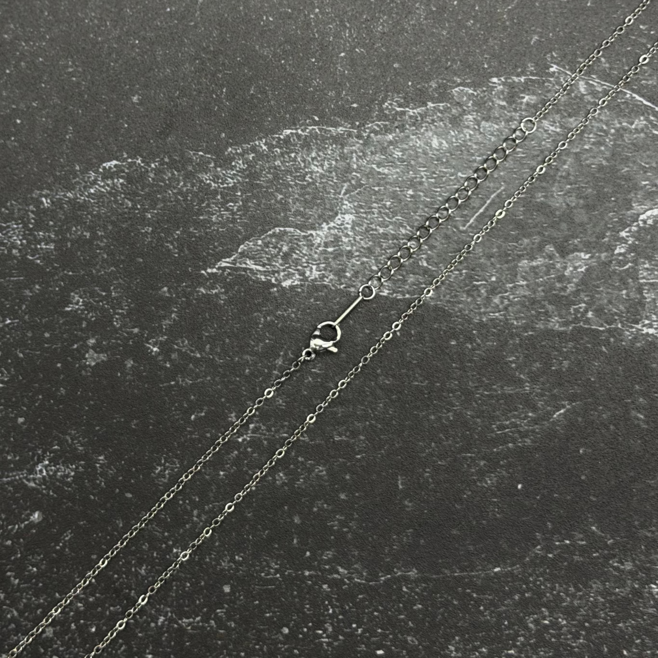 Stainless steel chain necklace on black surface. 