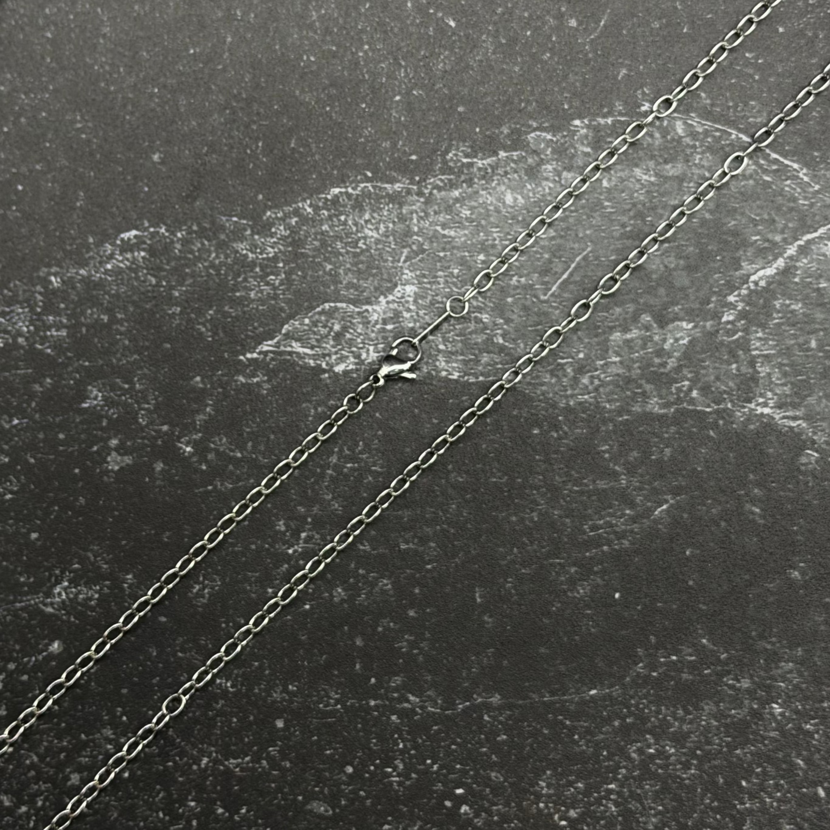 Stainless steel chain necklace on black surface. 