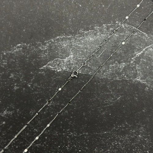 Stainless steel chain with lobster clasp on dark surface