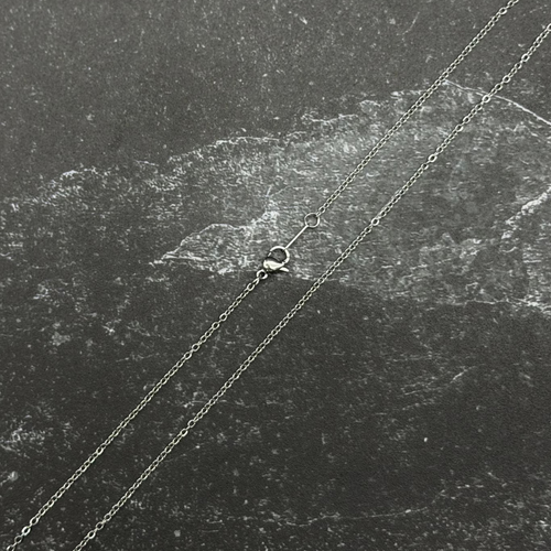 Stainless steel chain with lobster clasp on dark surface.