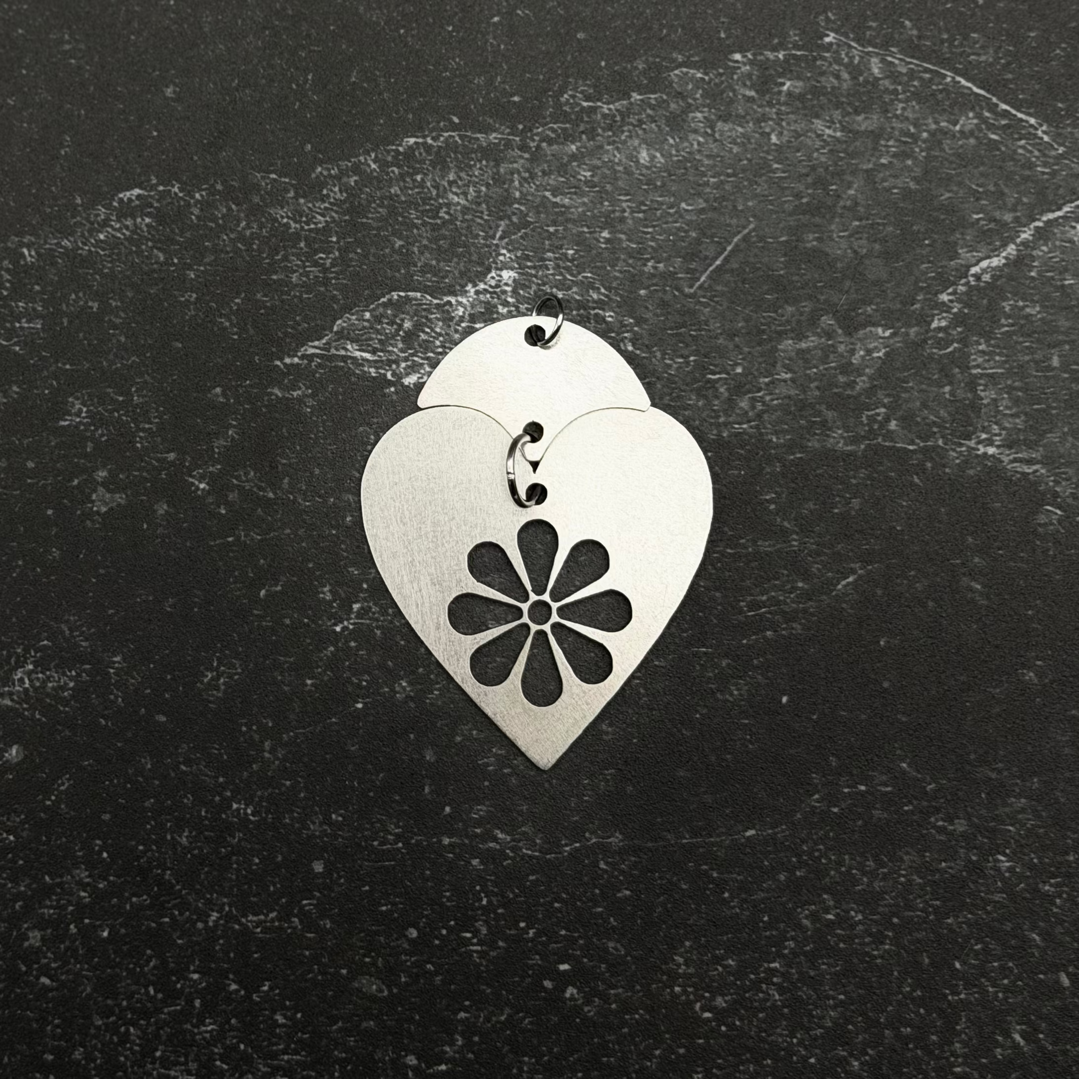 Stainless steel Heart-shaped pendant with floral design on a dark textured background