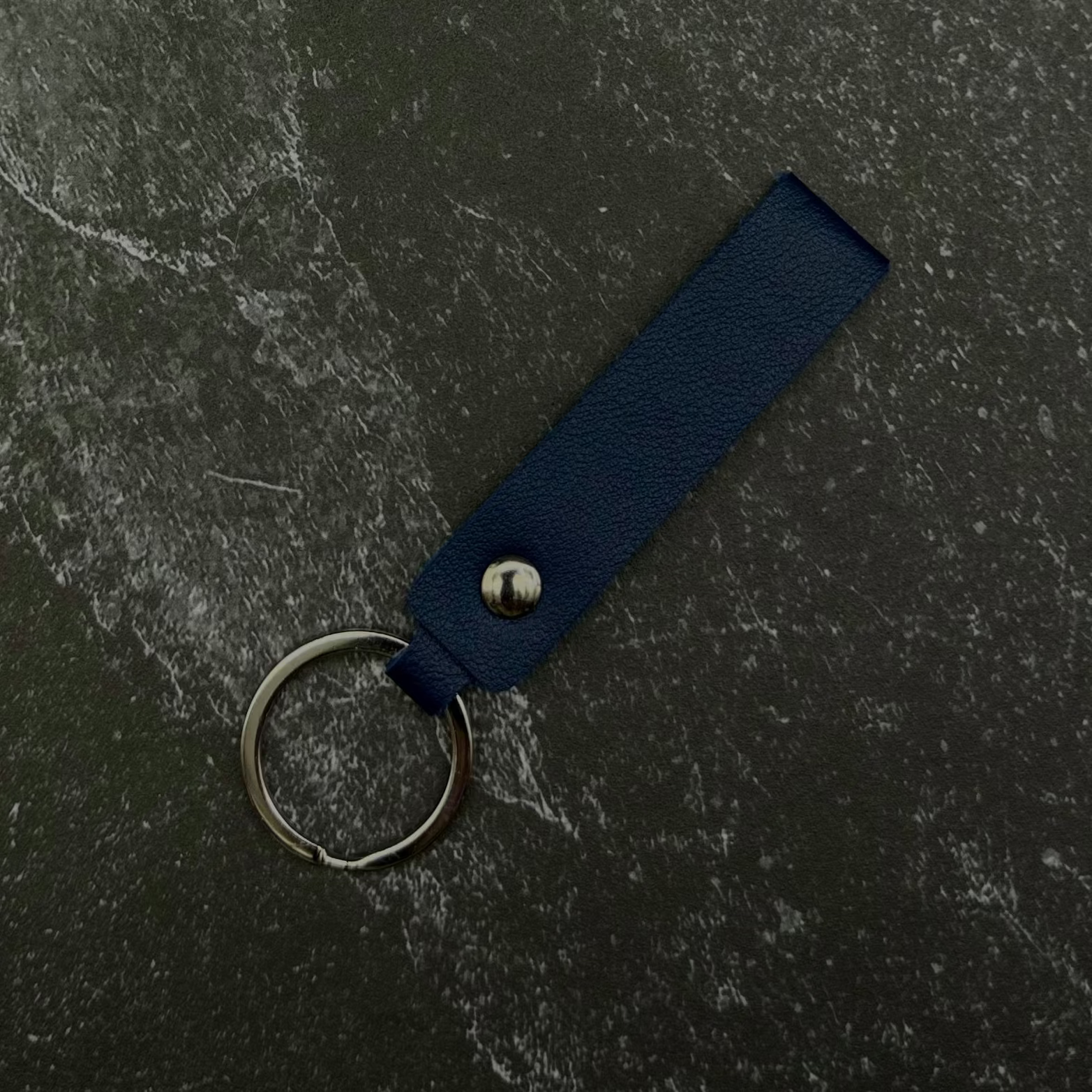 blue keychain attached to a dark fabric background