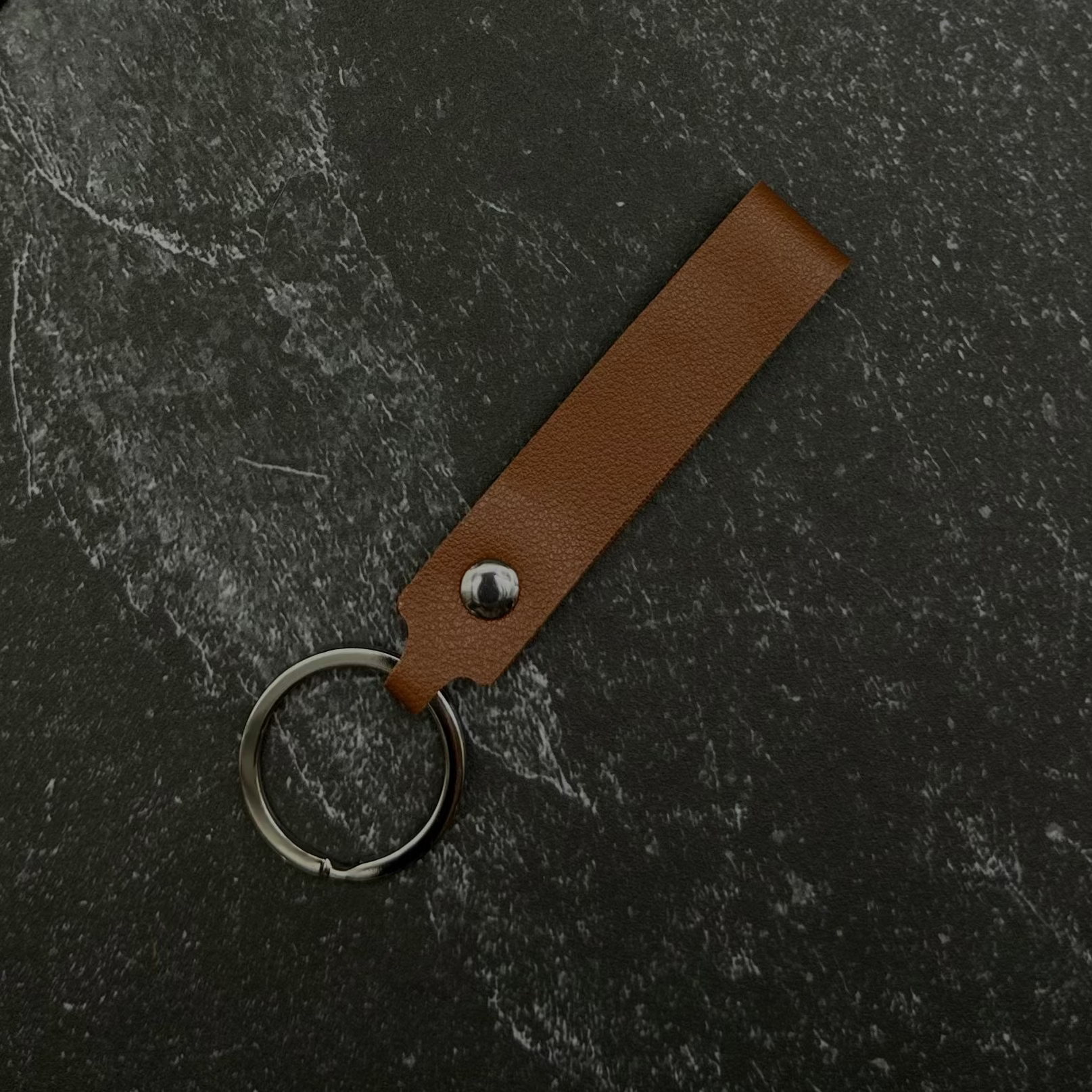 brown leather keychain on a black surface