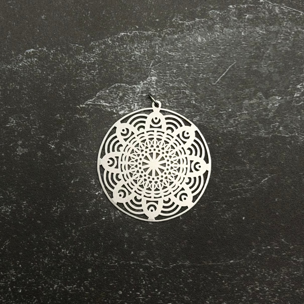 Stainless steel mandala pendant on a black textured surface