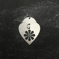 Stainless steel heart-shaped pendant with floral design on a dark textured background