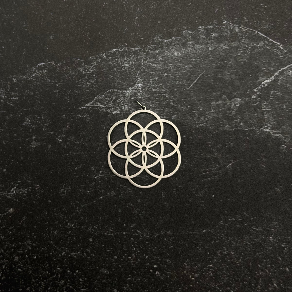 Stainless steel seed of life pendant on stone surface. 
