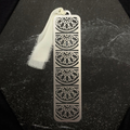 Stainless steel horizon bookmark with intricate patterns on a black surface
