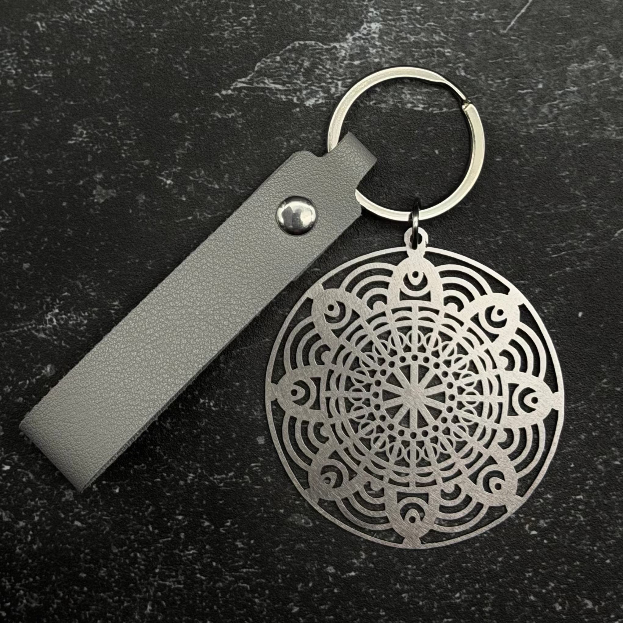 Stainless steel Keychain with geometric design on a dark surface
