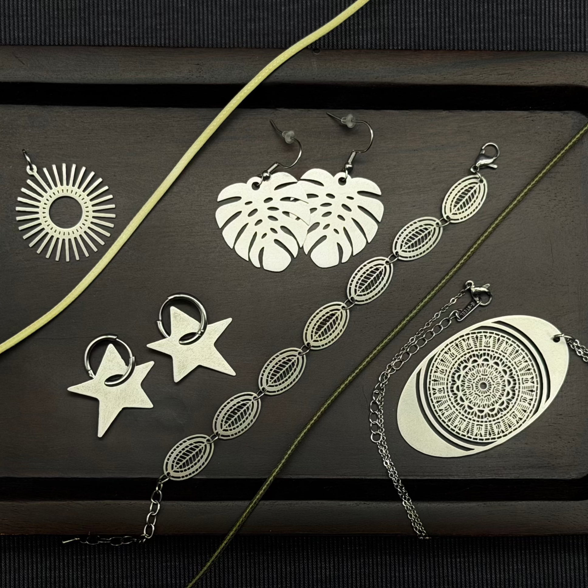 Collection of stainless steel jewelry including necklaces and earrings on a dark surface