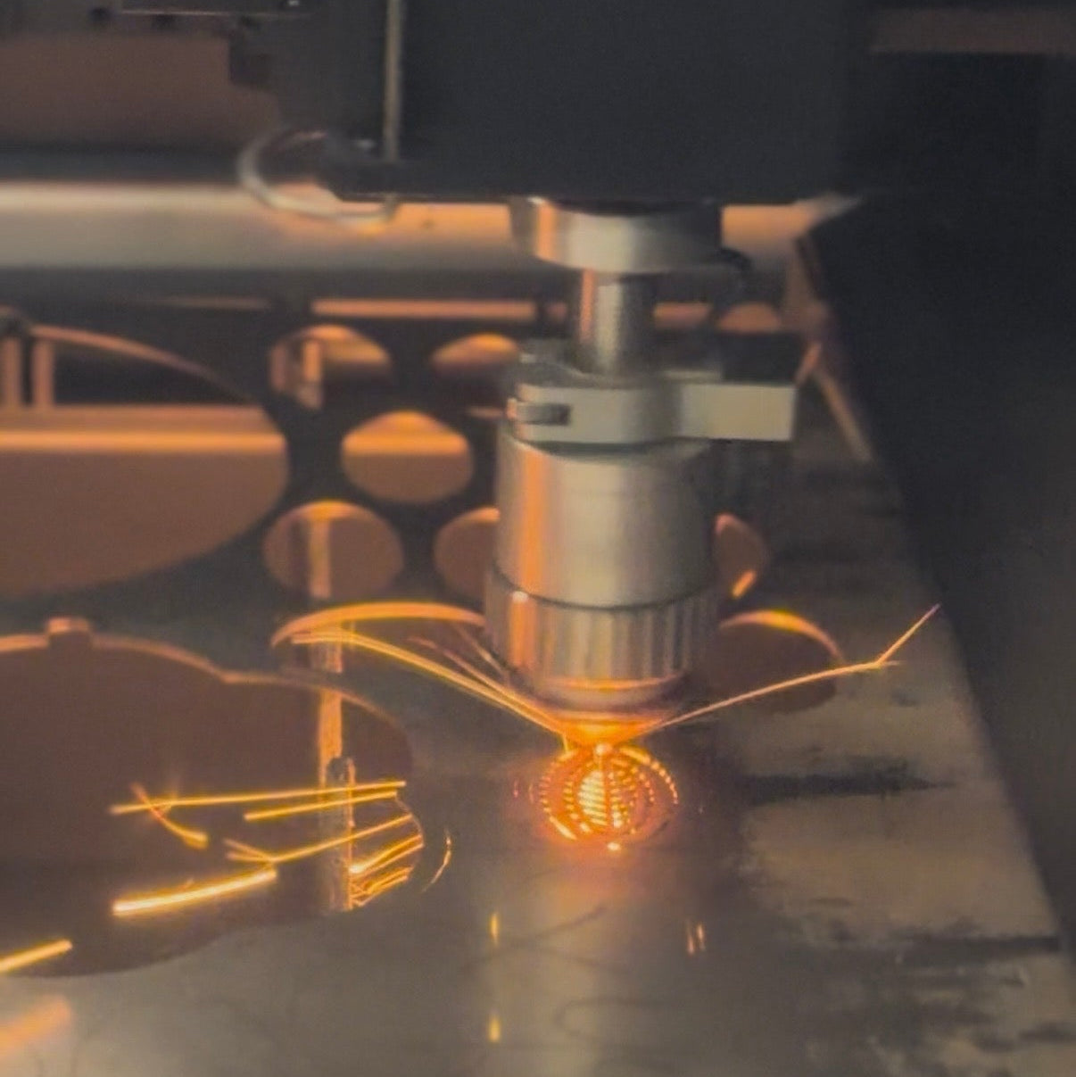 Close-up of a laser cutting machine in action cutting a leaf with sparks flying.