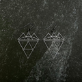 Geometric earrings on a dark stone surface.
