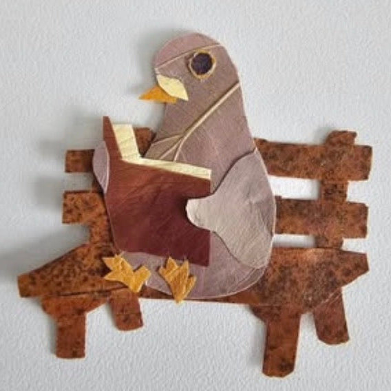 Decorative wall art of a bird reading a book on a branch.