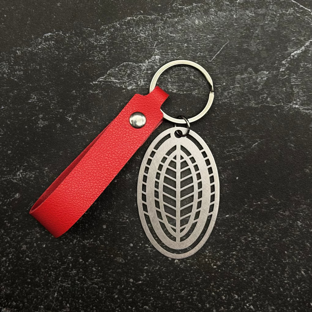 Stainless steel Keychain with red strap and silver leaf design on a dark surface