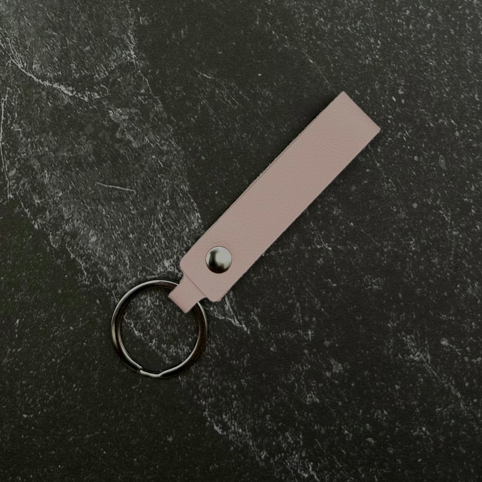 Light pink leather keychain on a black background