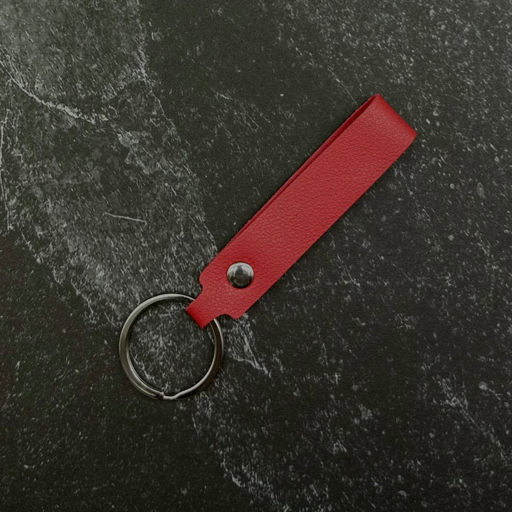 red leather keychain on a black stone background