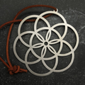 Stainless steel Decorative metal pendant with interlocking circles on a dark surface