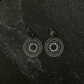 Pair of silver flower stacked circle earrings on a dark stone surface