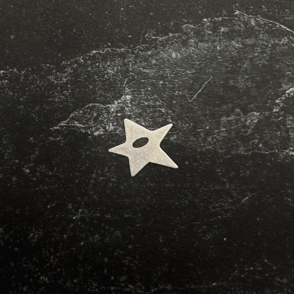 Stainless steel start pendant on a textured black surface