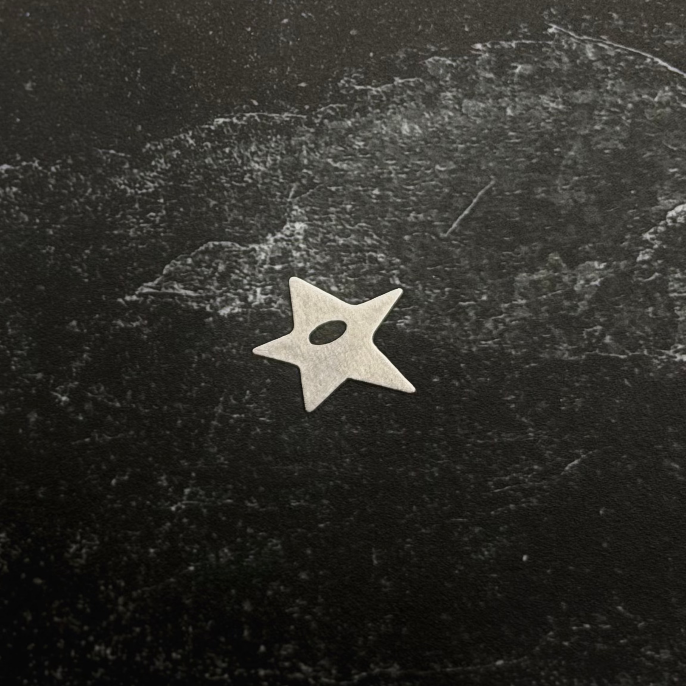 Stainless steel start pendant on a textured black surface