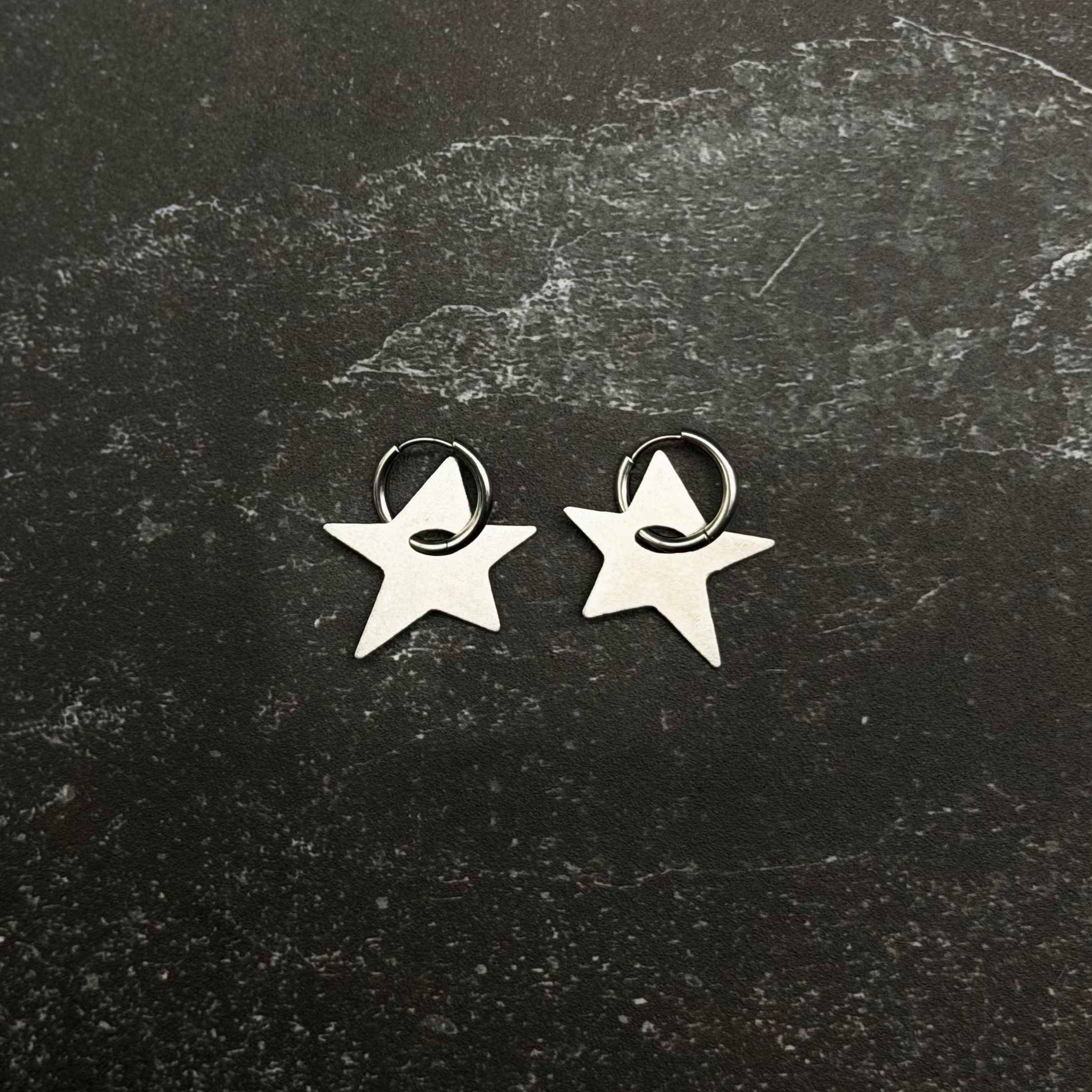 Stainless steel Star-shaped earrings on a textured black surface