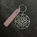 Floral design key chain with pink leather strap on a dark surface