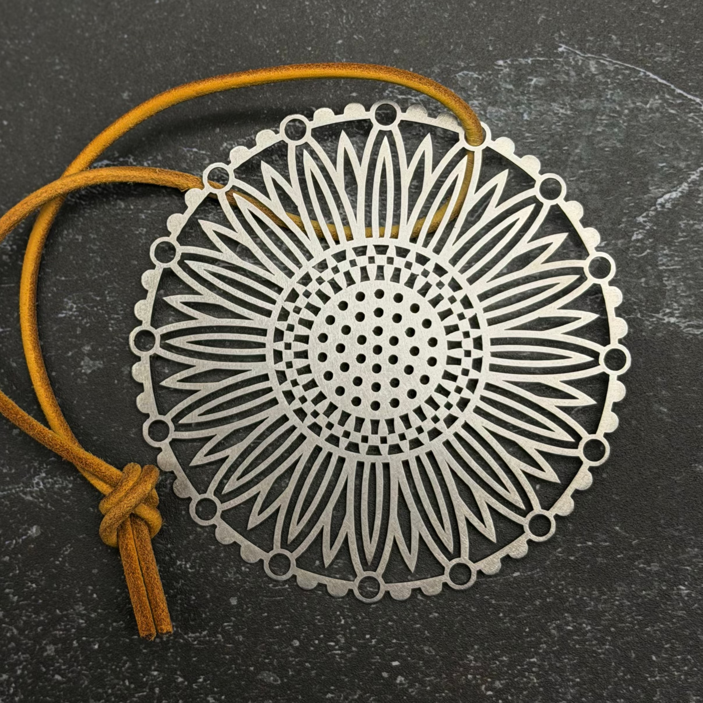 Stainless steel Decorative metal pendant with intricate design on a dark surface
