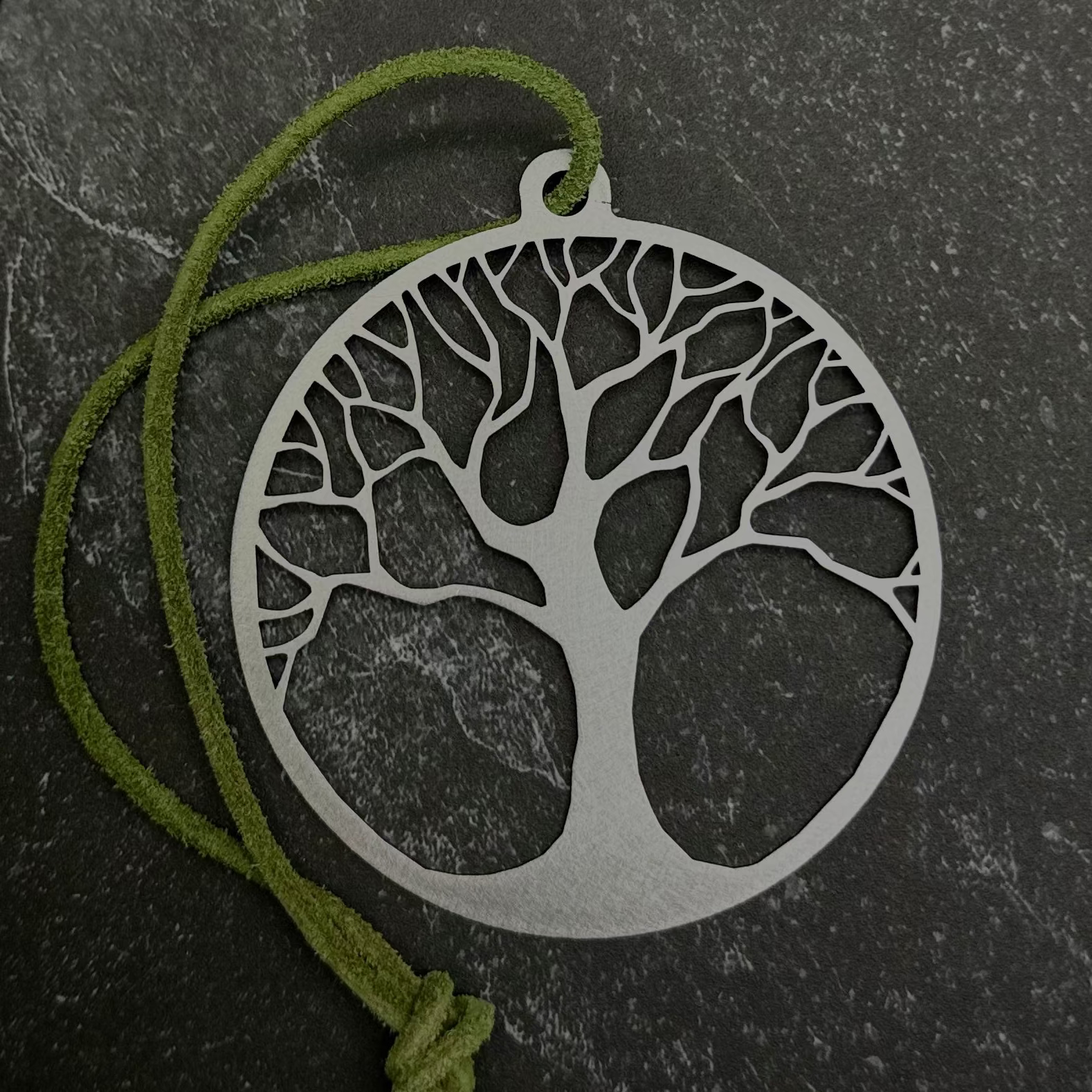 Tree of life ornament and green cord on a black background