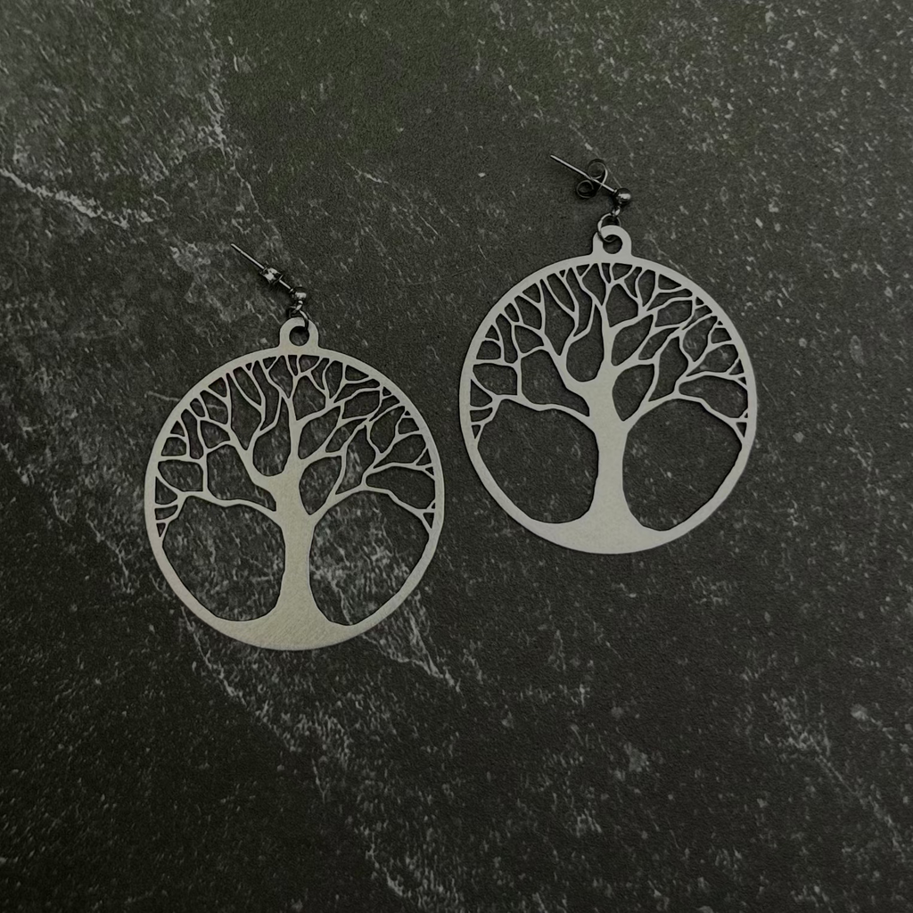 Tree of Life earrings on a dark stone surface