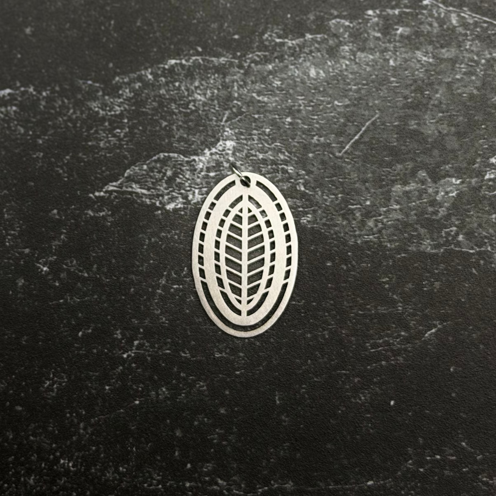 Stainless steel pendant with leaf design on a textured black surface