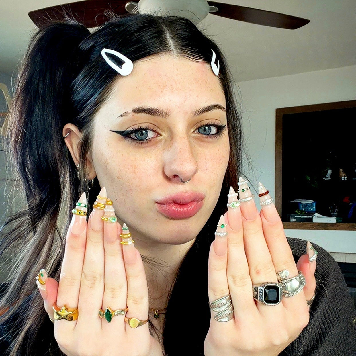 Woman displaying her hands with jewelry in a room with a ceiling fan.