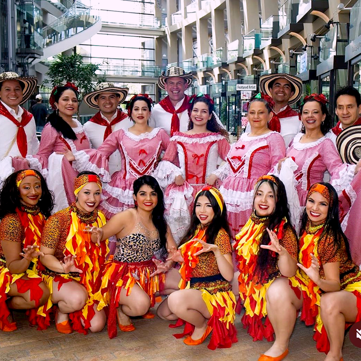 Colombian group of people in colorful costumes posing for a photo in an indoor setting.