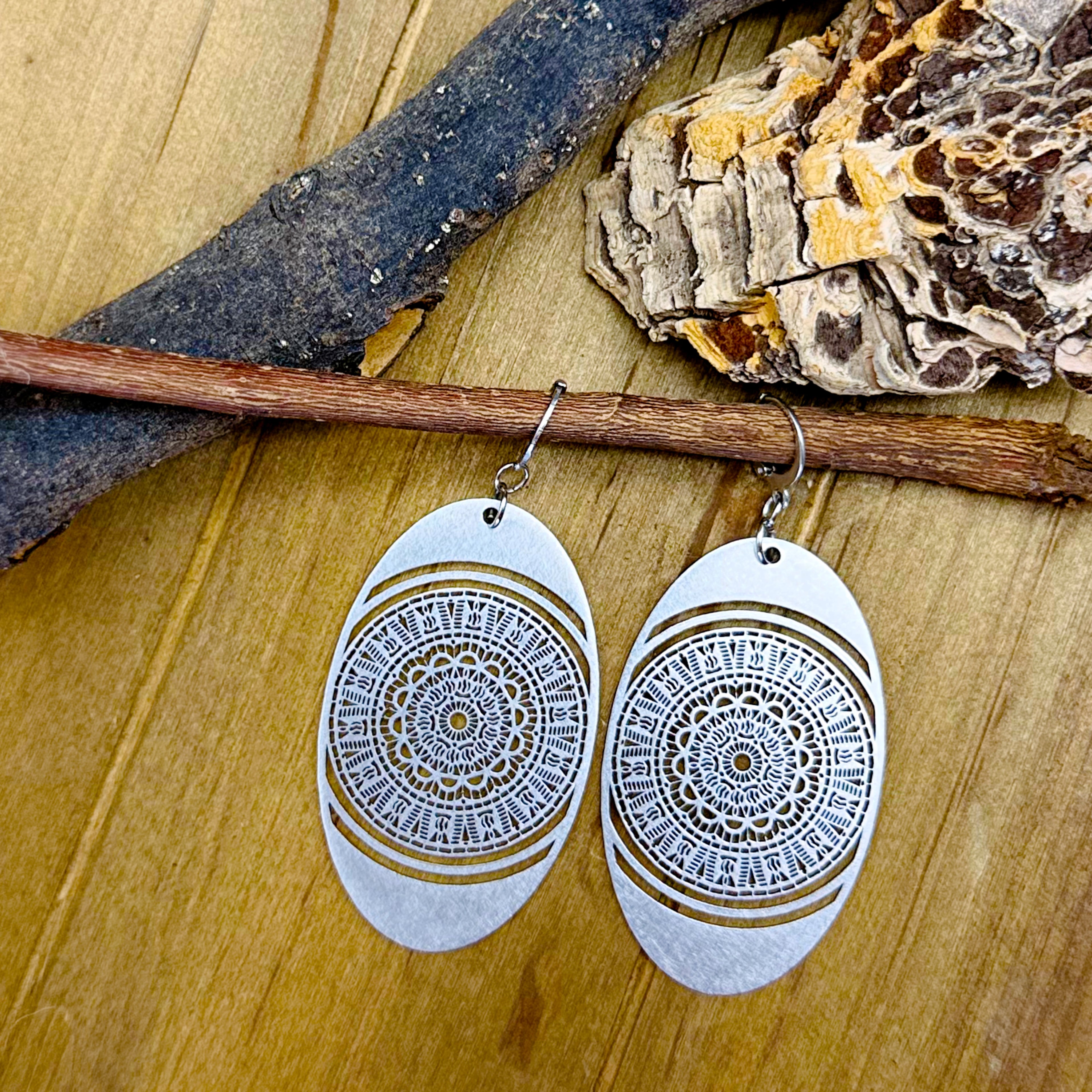 Pair of earrings with intricate design on a wooden surface
