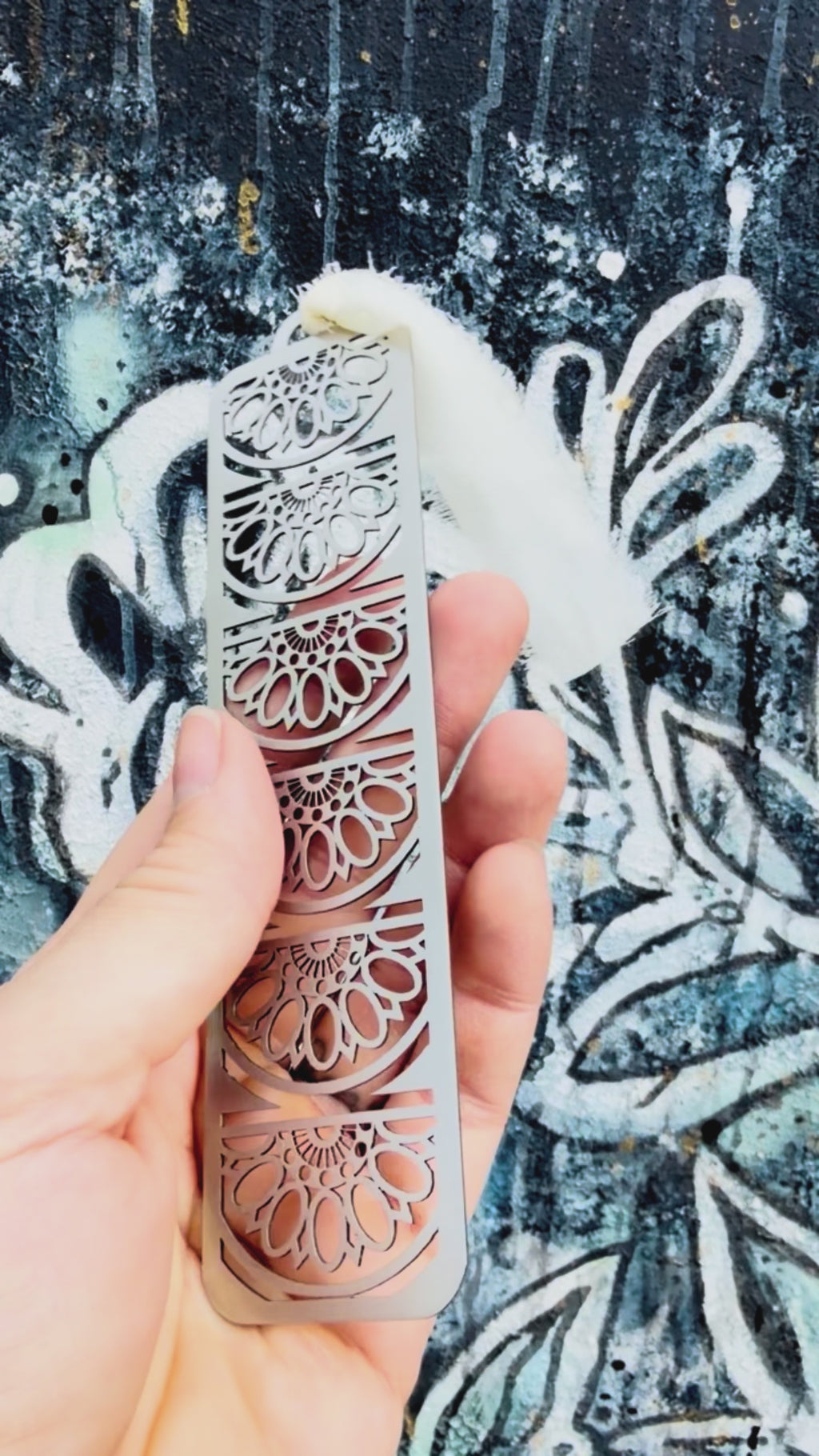 Stainless steel sun fan mandala bookmark with textured background. 