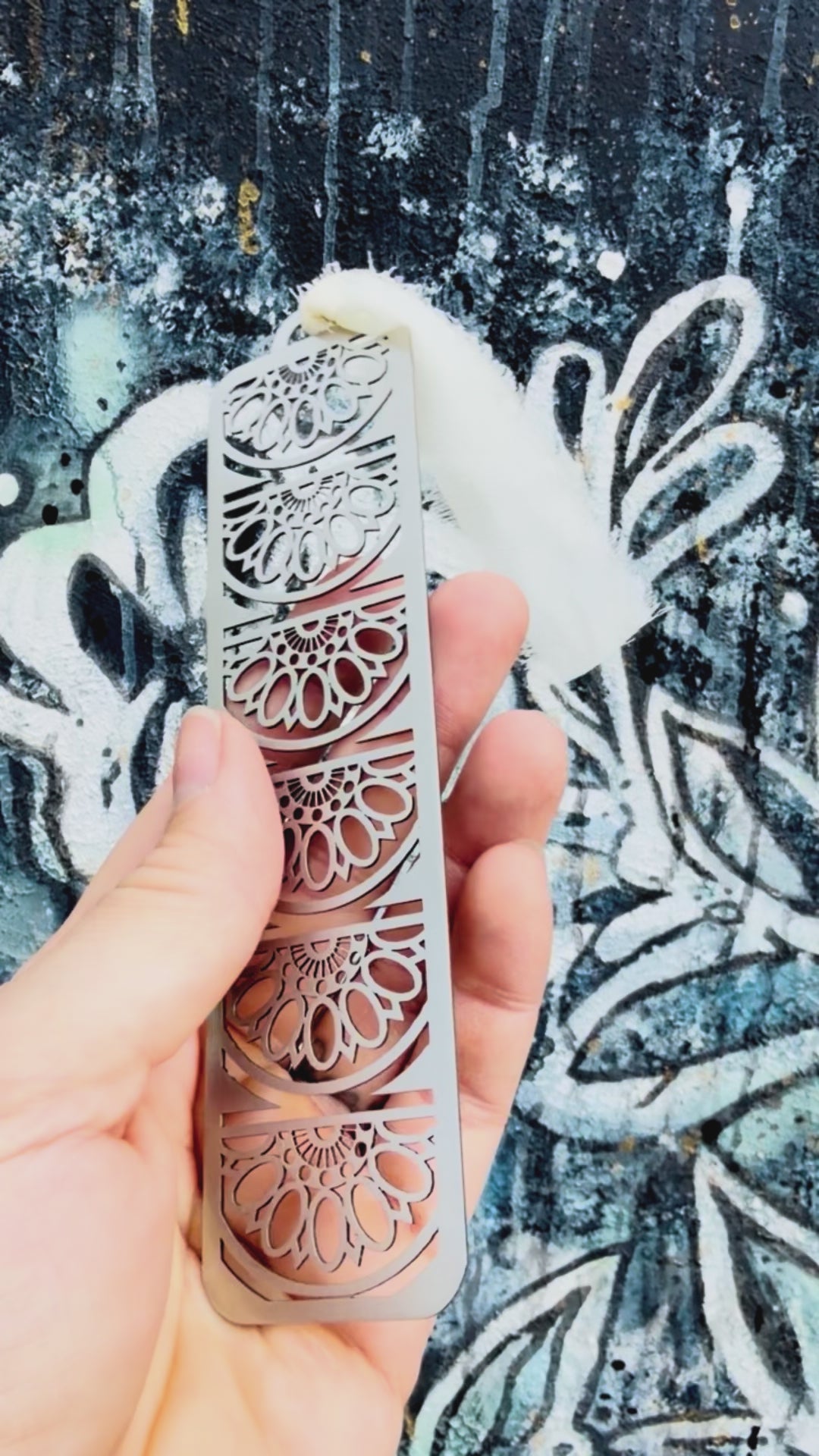 Stainless steel sun fan mandala bookmark with textured background. 