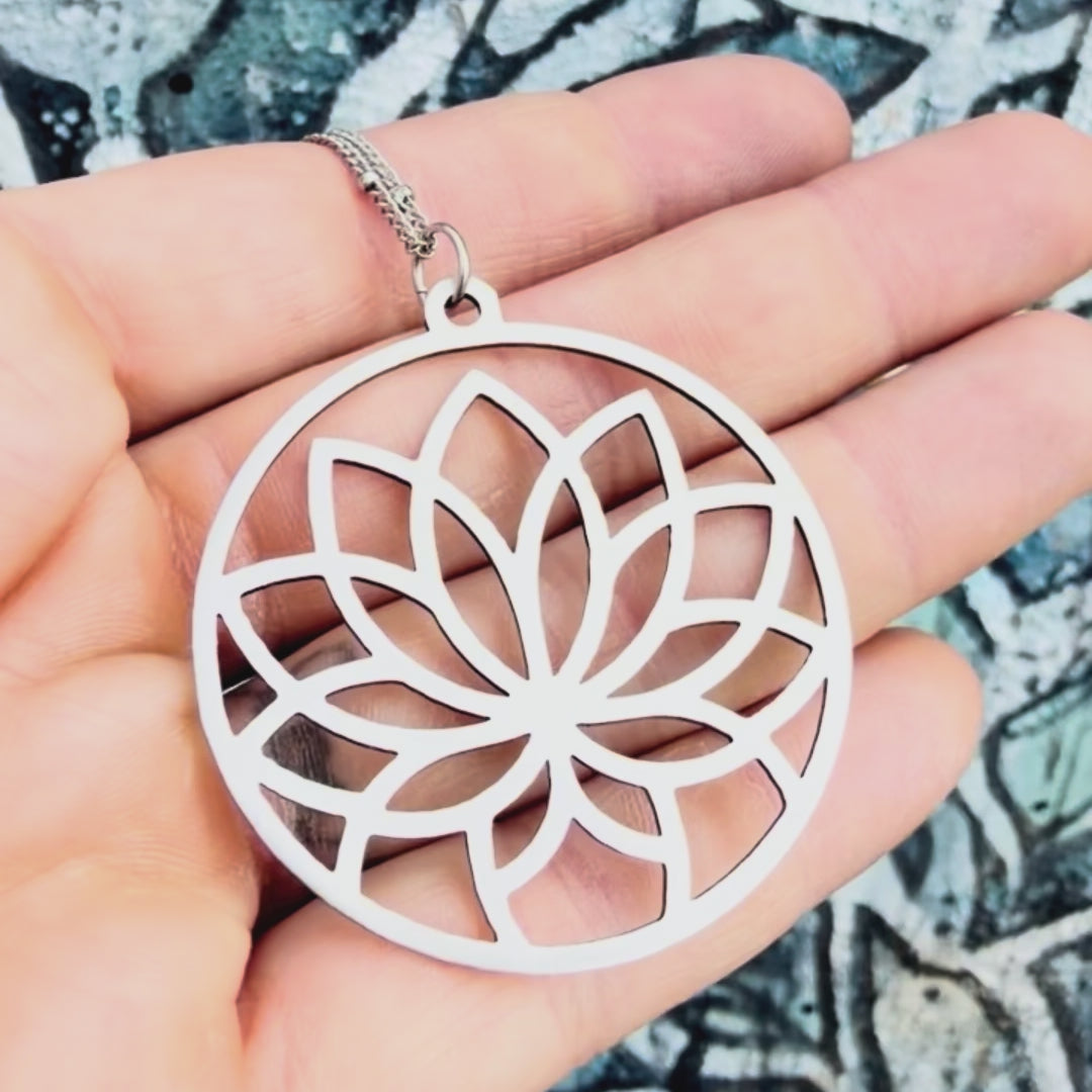 Stainless steel flower mandala pendant with textured background. 