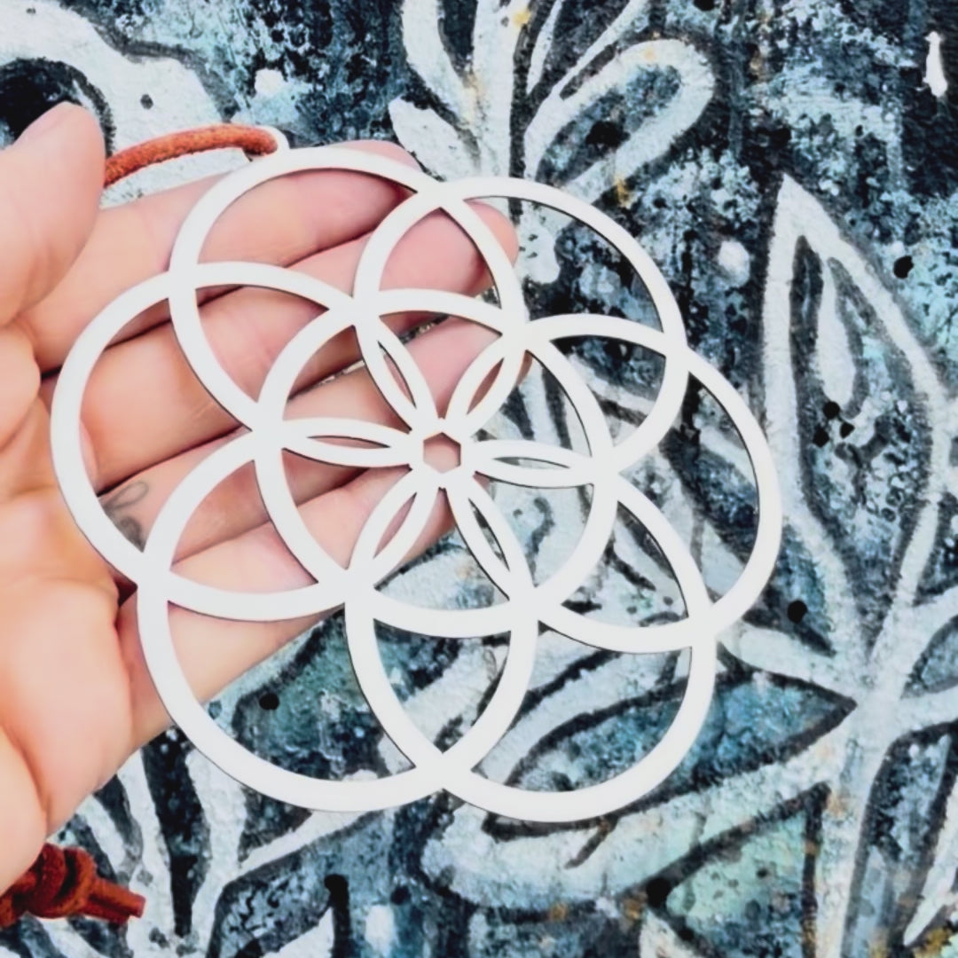 Stainless steel seed of life key chain with textured background. 