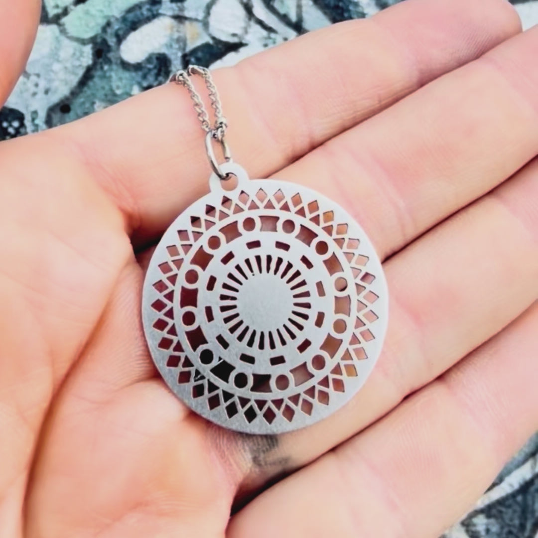 Stainless steel mosaic pendant with textured background. 