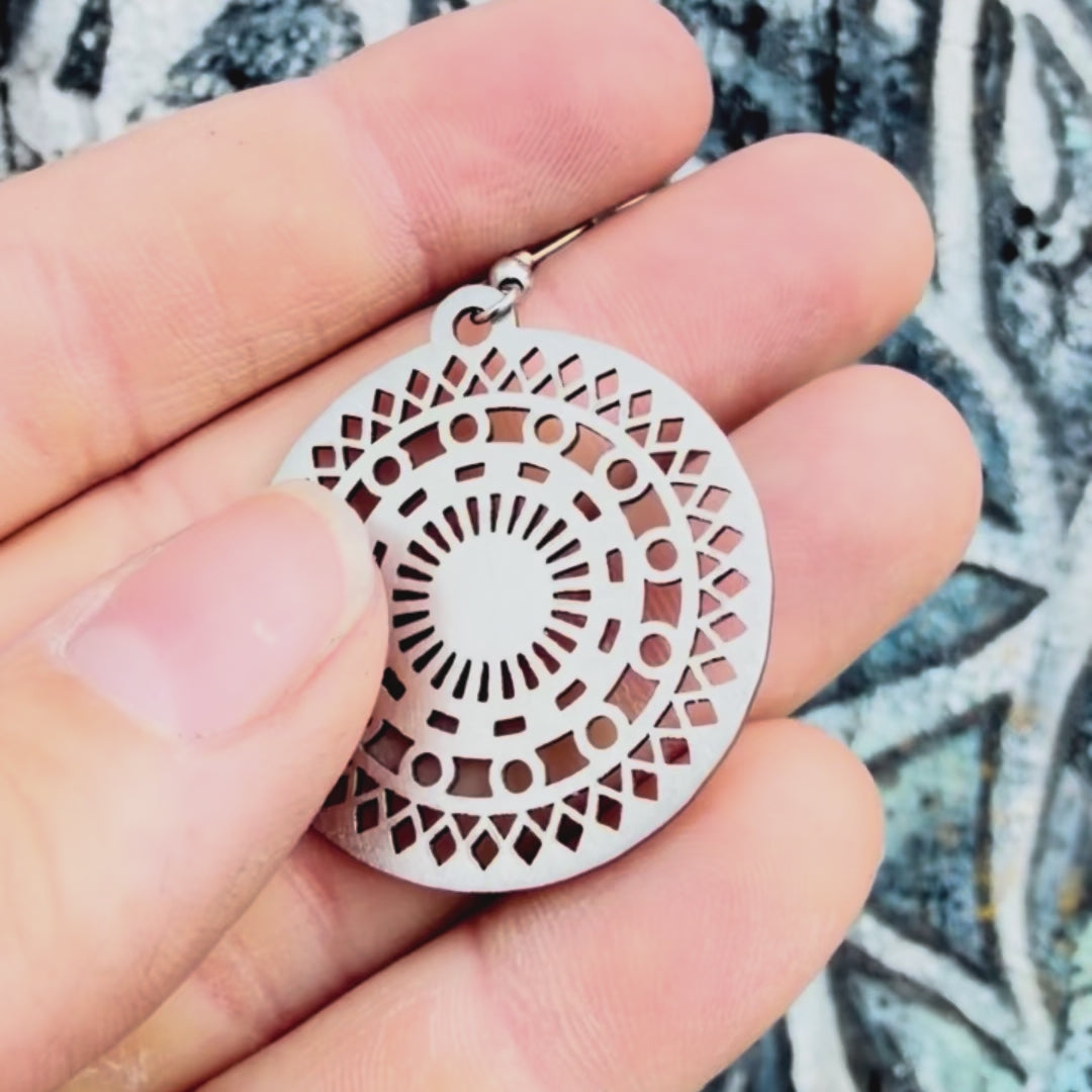 Stainless steel mosaic mandala earring with textured background. 