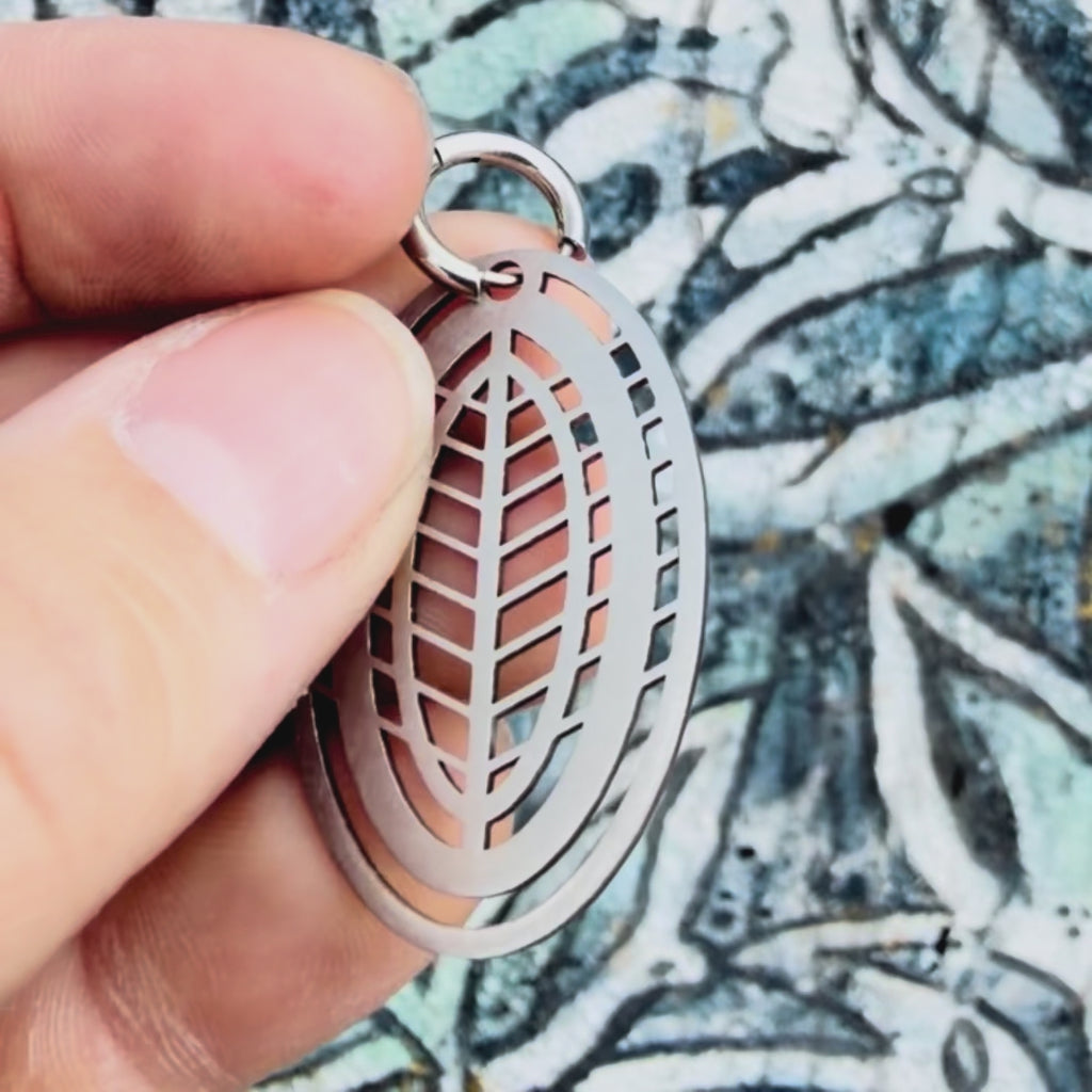 Stainless steel leaf geometric earring with textured background. 
