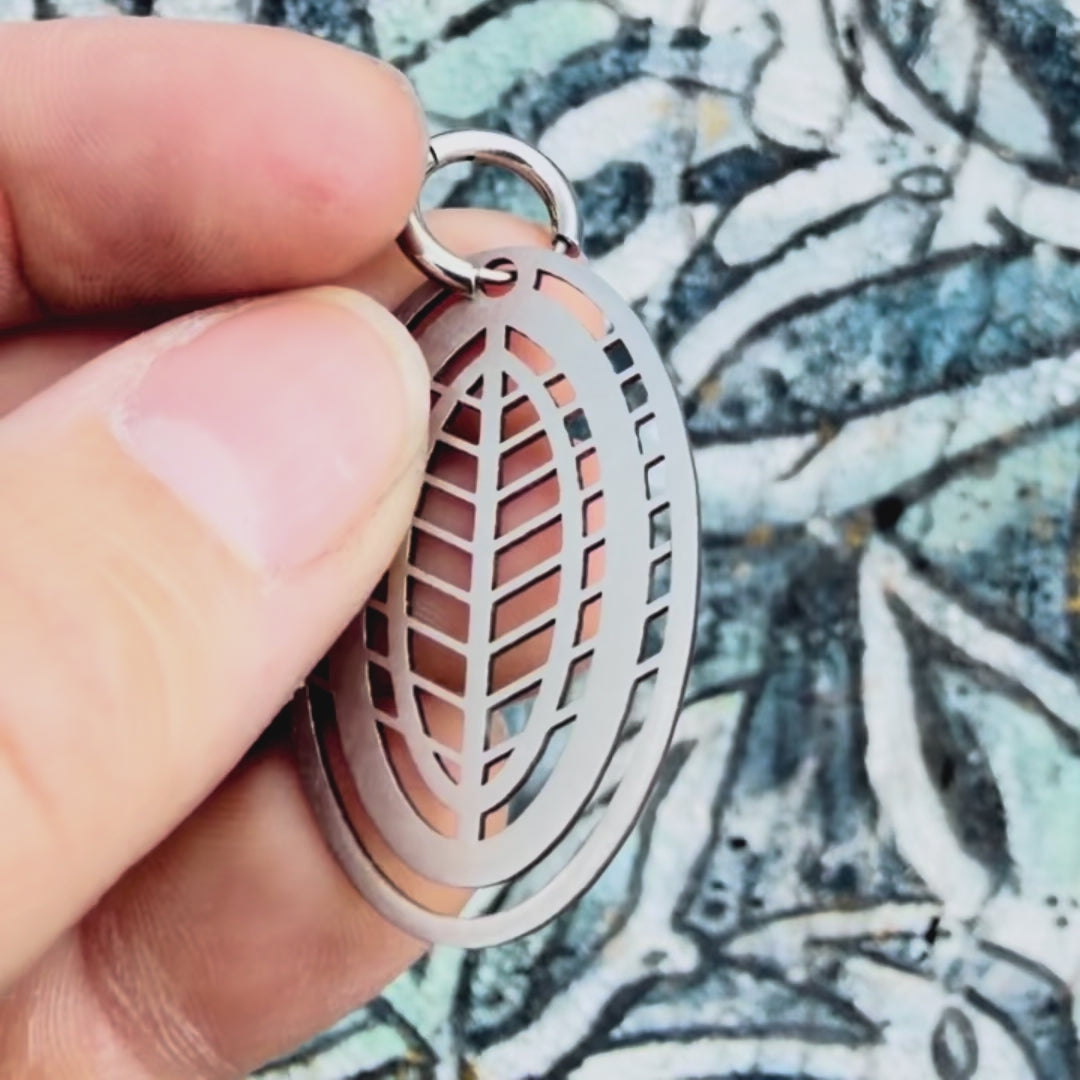 Stainless steel leaf geometric earring with textured background. 
