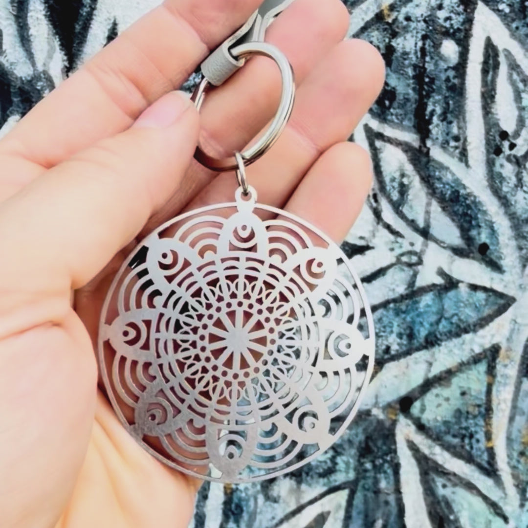 Stainless steel flower mandala key chan with textured background. 
