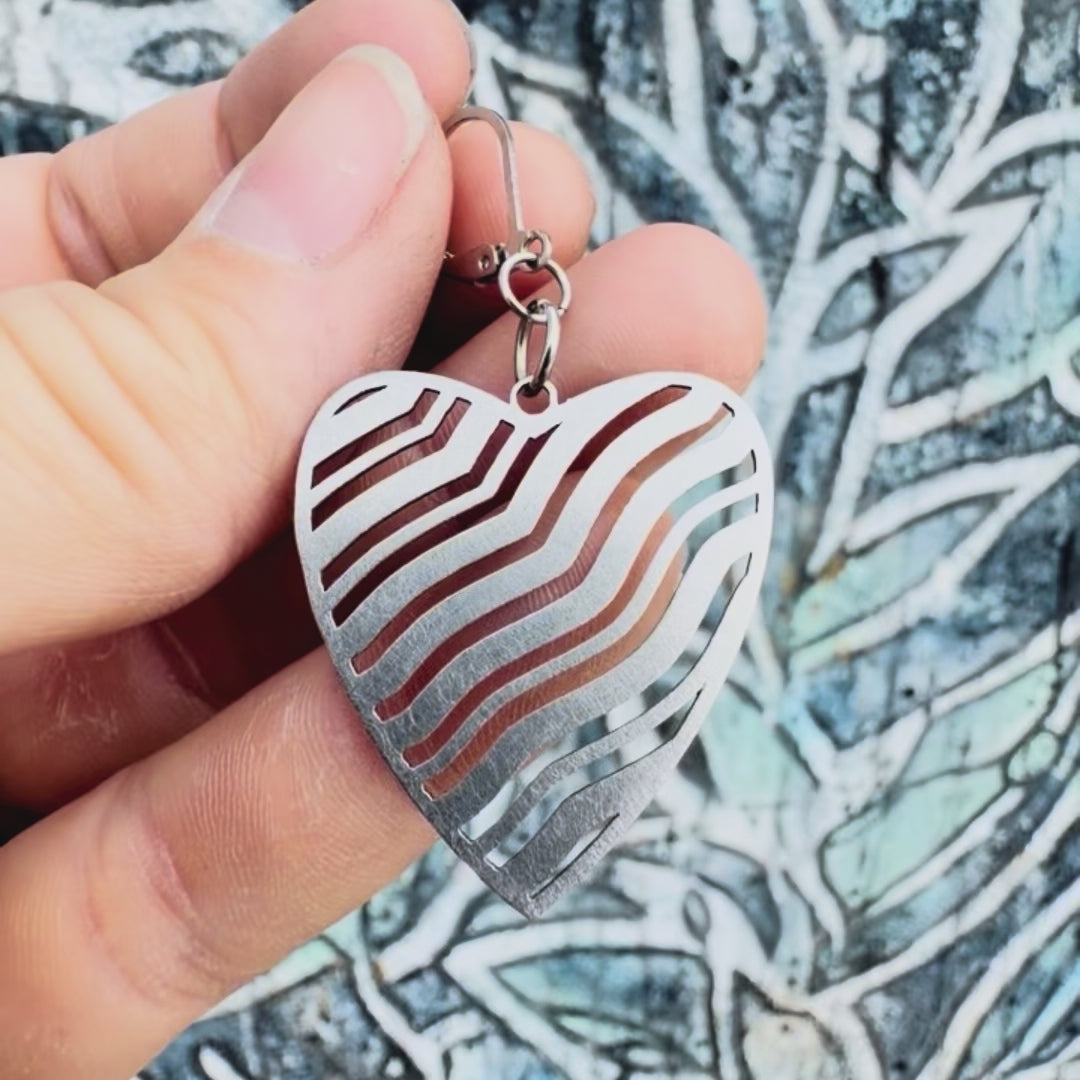 Stainless steel wavy heart earring with textured background. 