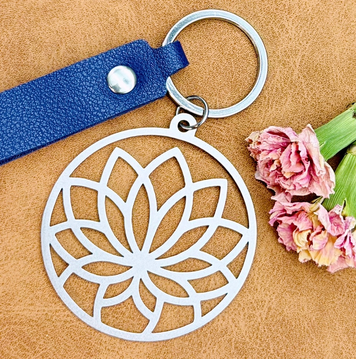Keychain with lotus flower design on a brown background with flowers