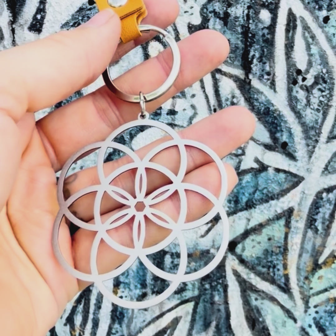 Stainless steel seed of life key chain with textured background. 