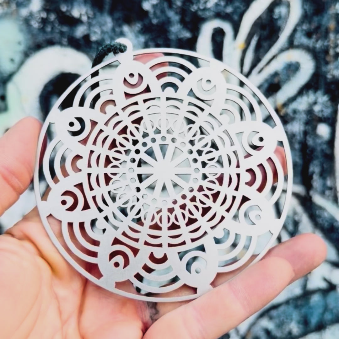 Stainless steel flower mandala car charm with textured background. 