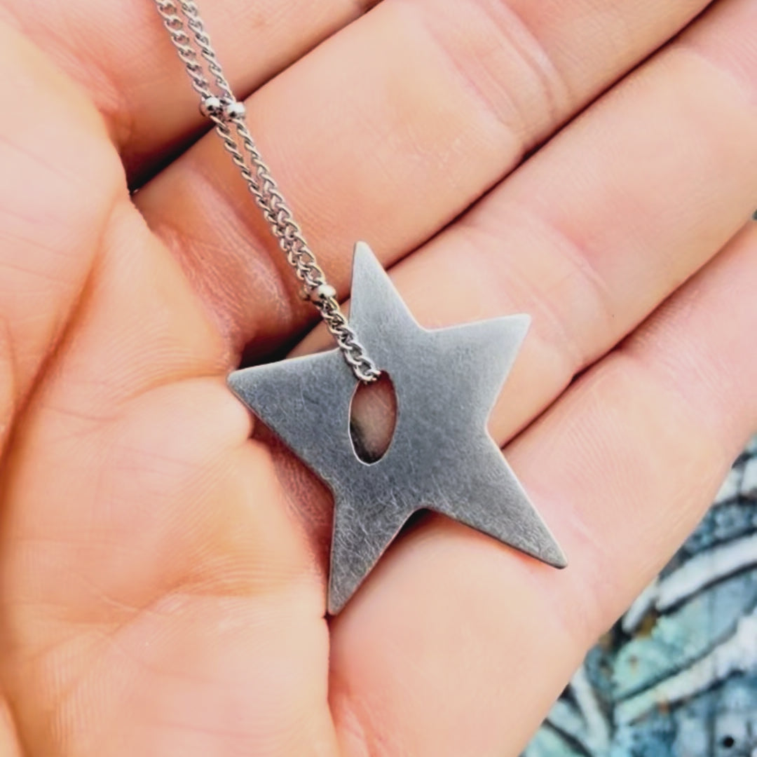Stainless steel star pendant with textured background. 