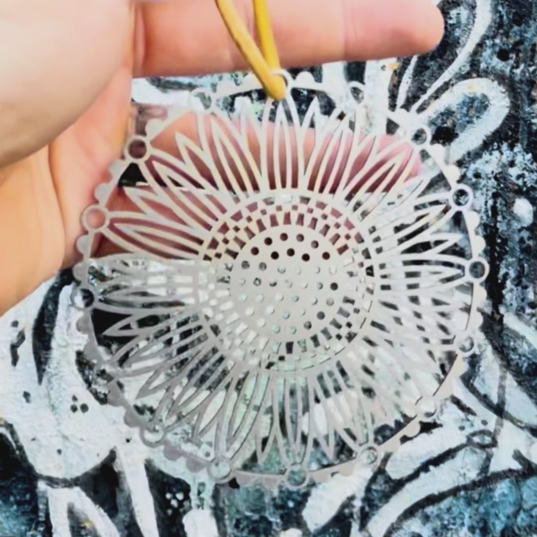 Stainless steel sunflower mandala car charm with textured background. 